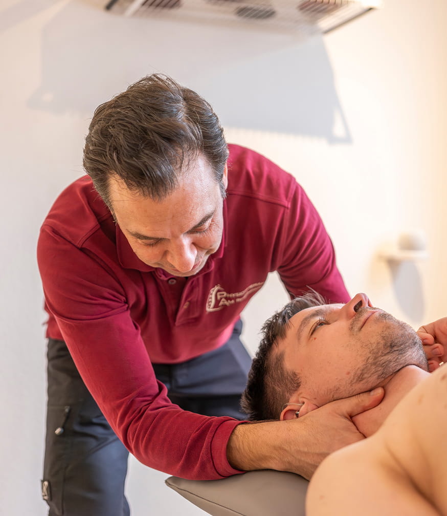 Physiotherapeut behandelt den Nacken eines liegenden Patienten in der Praxis am Rheinpark