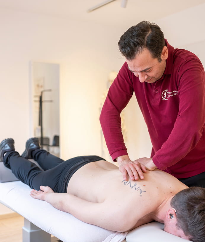 Physiotherapeut behandelt den unteren Rücken eines liegenden Patienten