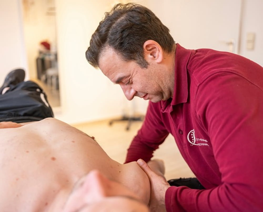 Physiotherapeut behandelt den Rücken eines liegenden Patienten