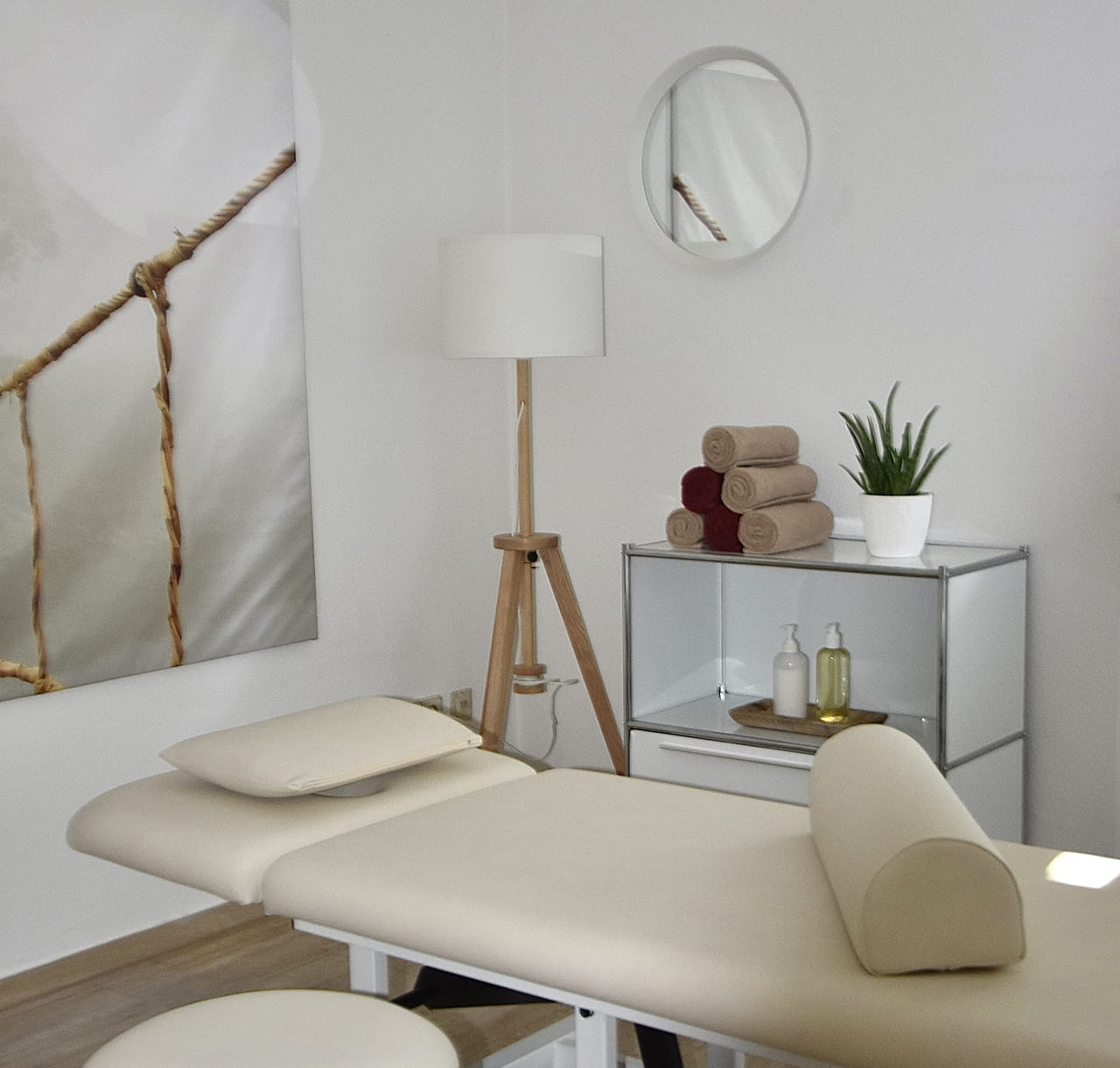 Behandlungsraum mit Therapieliege, Nackenrolle und frischen Handtüchern