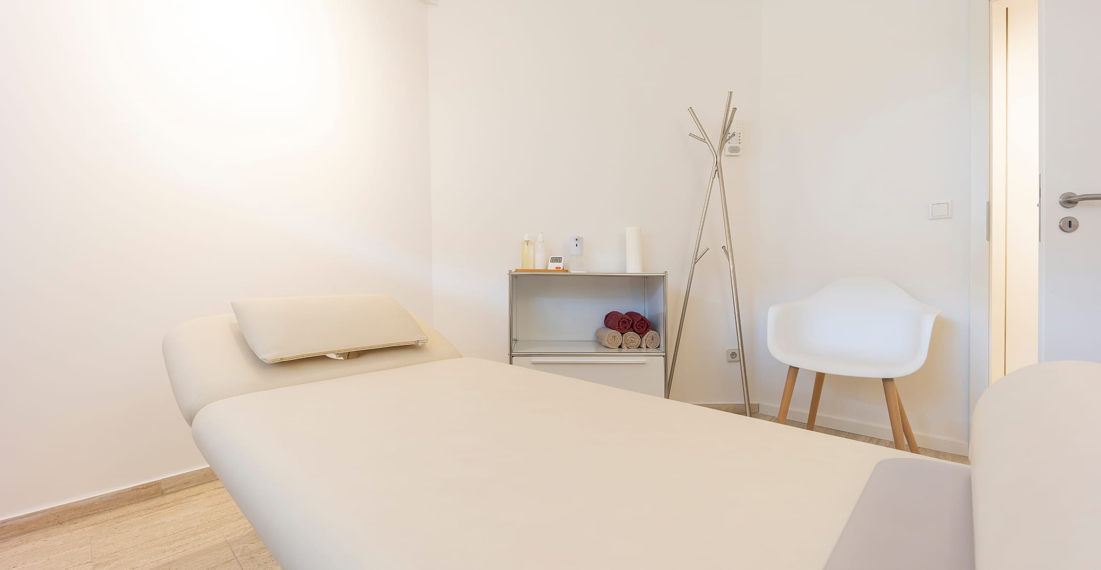 Heller Behandlungsraum mit Therapieliege und Garderobe